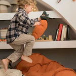 A large, orange, carrot-shaped bean bag with a green leaf on top, made of cotton fabric, kids bean bags and poufs singapore