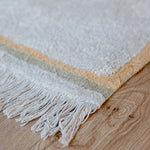 A rectangular, flatweave washable rug in beige, pink, and gray tones with a minimalistic geometric pattern, kids rugs and carpets singapore