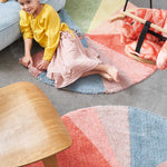 A round wool rug with a colorful pie chart design, featuring shades of green, blue, red, and gray, rainbow rug, kids rugs and carpets Singapore