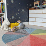 A round wool rug with a colorful pie chart design, featuring shades of green, blue, red, and gray, rainbow rug, kids rugs and carpets Singapore