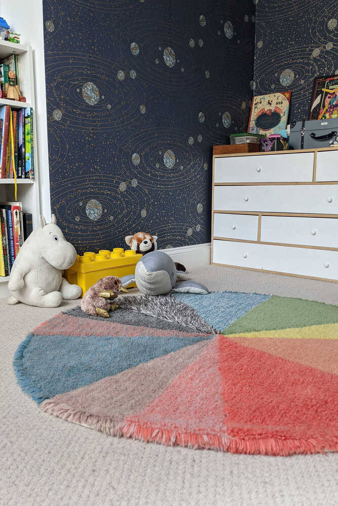 A round wool rug with a colorful pie chart design, featuring shades of green, blue, red, and gray, rainbow rug, kids rugs and carpets Singapore
