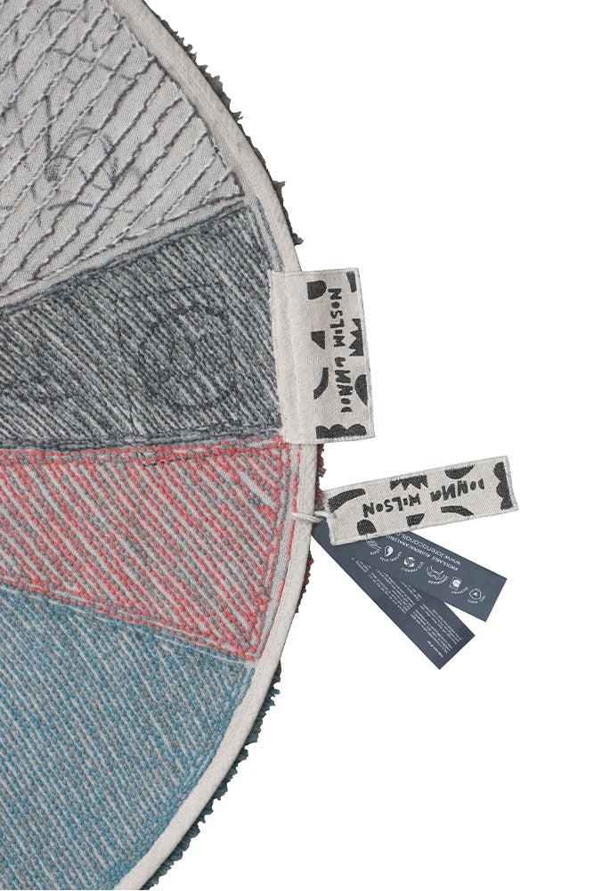 A round wool rug with a colorful pie chart design, featuring shades of green, blue, red, and gray, rainbow rug, kids rugs and carpets Singapore