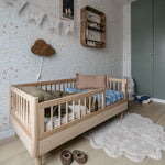 A toddler bed made from European oak with protective railings on all around, featuring a natural wood finish. Available in Singapore.