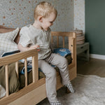 A toddler bed made from European oak with protective railings on all around, featuring a natural wood finish. Available in Singapore.