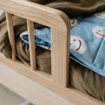 A toddler bed made from European oak with protective railings on all around, featuring a natural wood finish. Available in Singapore.