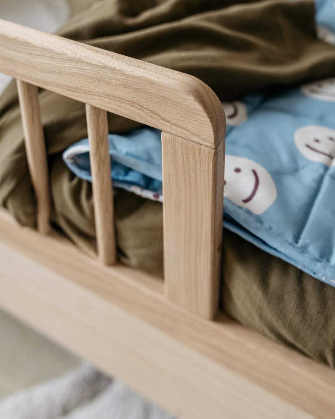 A toddler bed made from European oak with protective railings on all around, featuring a natural wood finish. Available in Singapore.