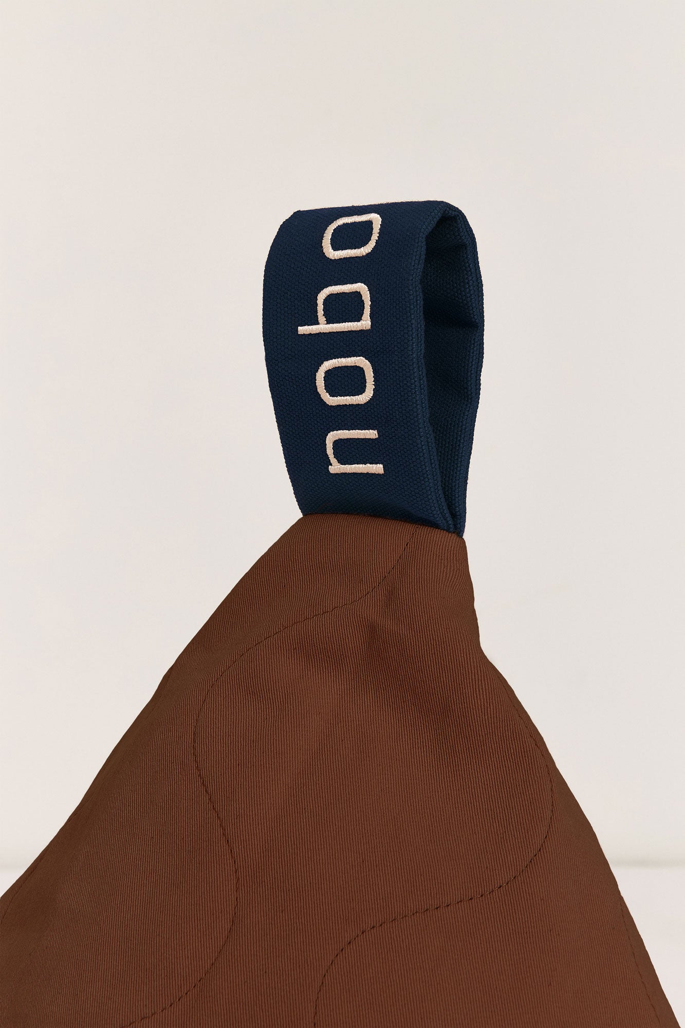 A brown quilted long beanbag with an embroidered handle, placed against a neutral background, kids bean bags and poufs in Singapore