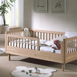 A toddler bed made from European oak with protective railings on all around, featuring a natural wood finish. Available in Singapore.