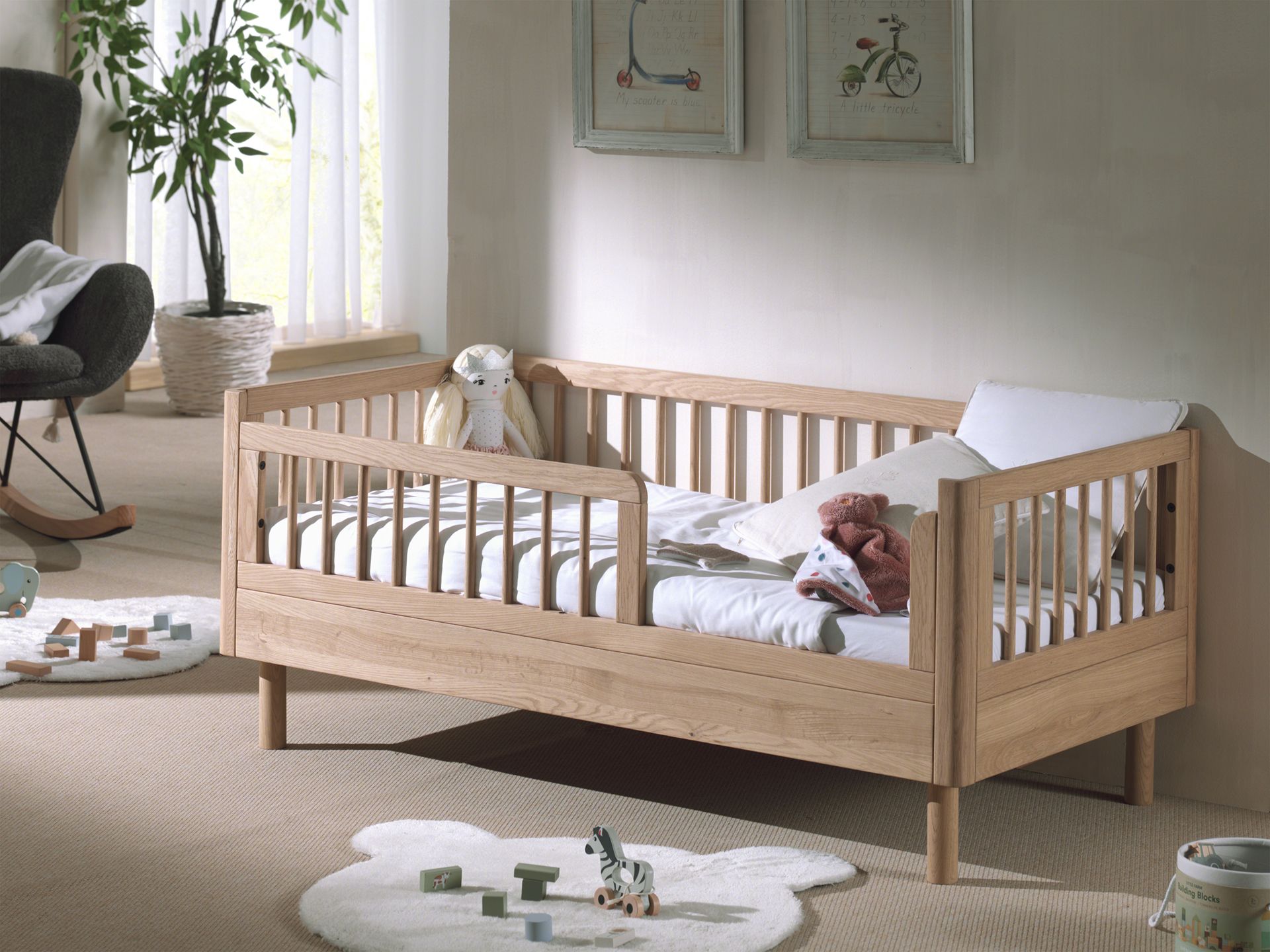 A toddler bed made from European oak with protective railings on all around, featuring a natural wood finish. Available in Singapore.
