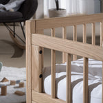 A toddler bed made from European oak with protective railings on all around, featuring a natural wood finish. Available in Singapore.
