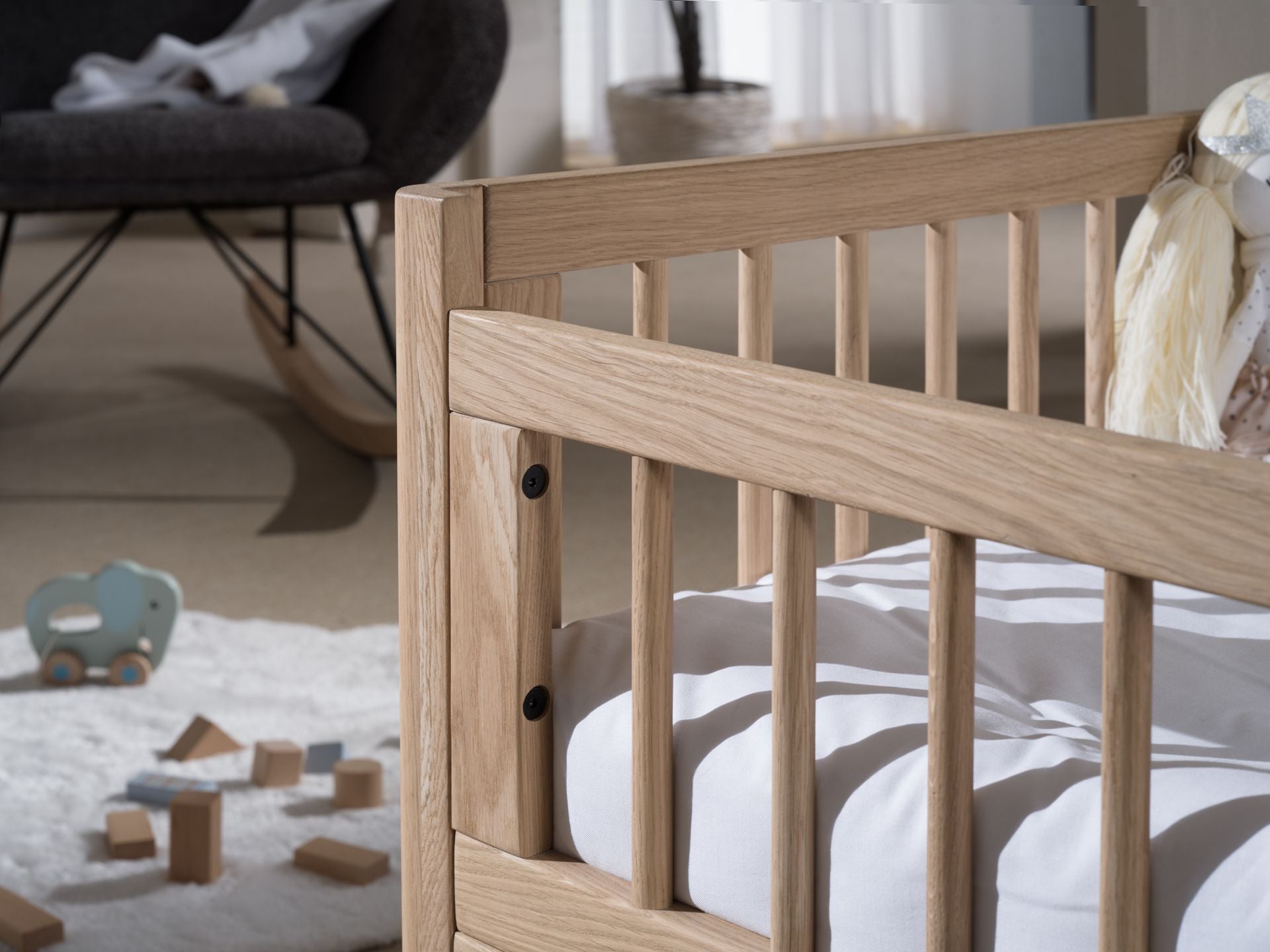 A toddler bed made from European oak with protective railings on all around, featuring a natural wood finish. Available in Singapore.