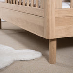 A toddler bed made from European oak with protective railings on all around, featuring a natural wood finish. Available in Singapore.