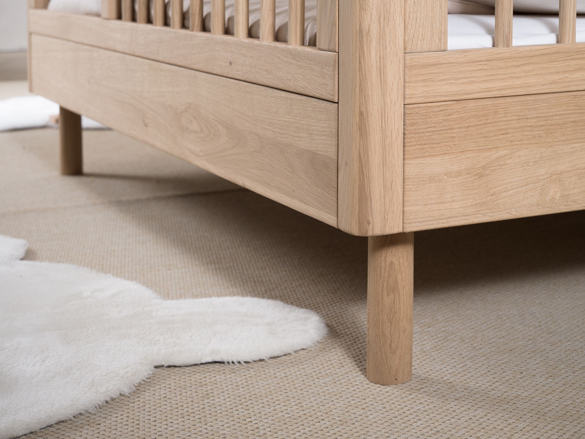 A toddler bed made from European oak with protective railings on all around, featuring a natural wood finish. Available in Singapore.