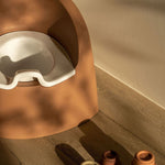 A brown Quax potty with a white inner bowl designed for toddlers, featuring a high backrest and anti-slip layer.