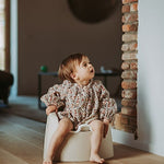 A beige Quax potty with a white inner bowl and high backrest, designed for toddlers.