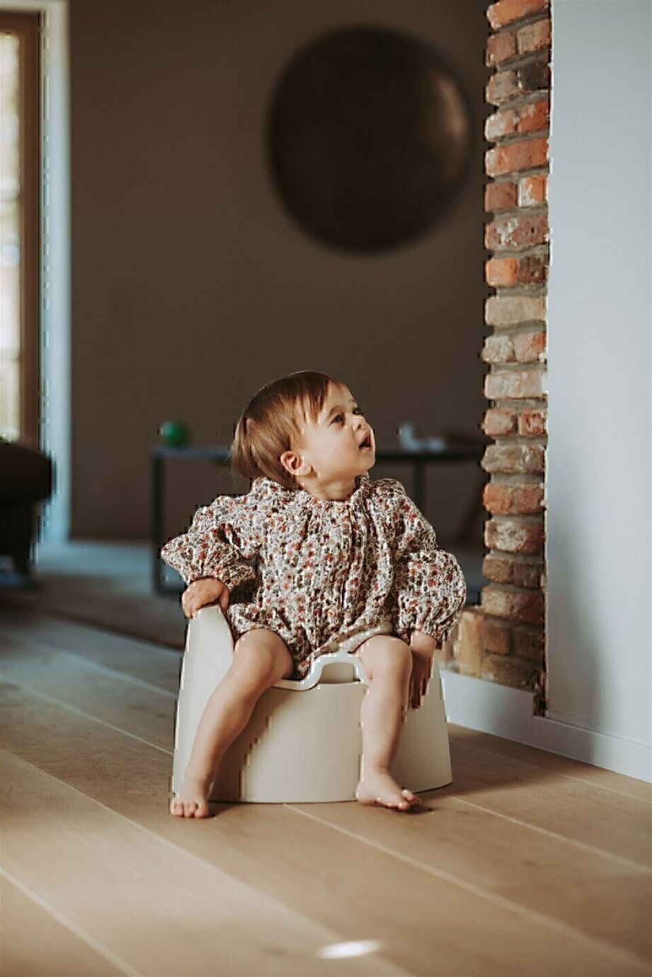 A beige Quax potty with a white inner bowl and high backrest, designed for toddlers.