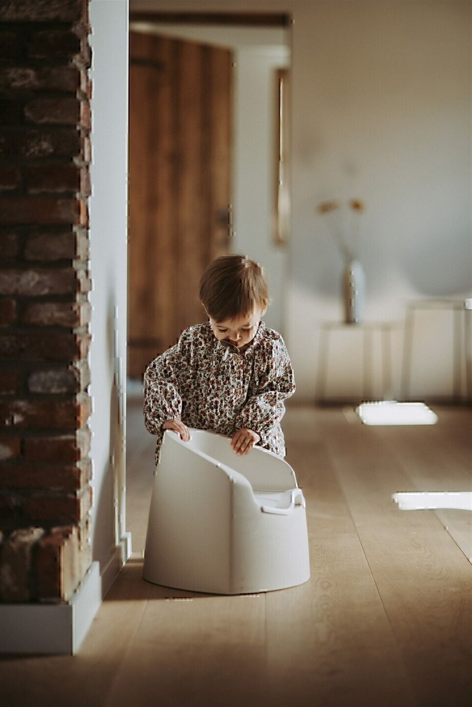 A beige Quax potty with a white inner bowl and high backrest, designed for toddlers.