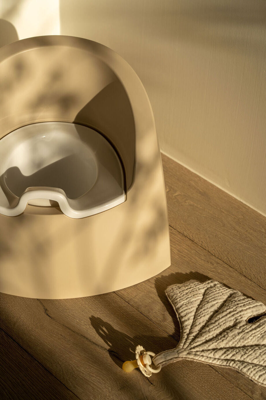 A beige Quax potty with a white inner bowl and high backrest, designed for toddlers.