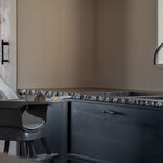 A Quax Ultimo High Chair in stone color with a modern design, featuring a high seat and adjustable legs, suitable for babies and toddlers.