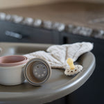 A Quax Ultimo High Chair in stone color with a modern design, featuring a high seat and adjustable legs, suitable for babies and toddlers.