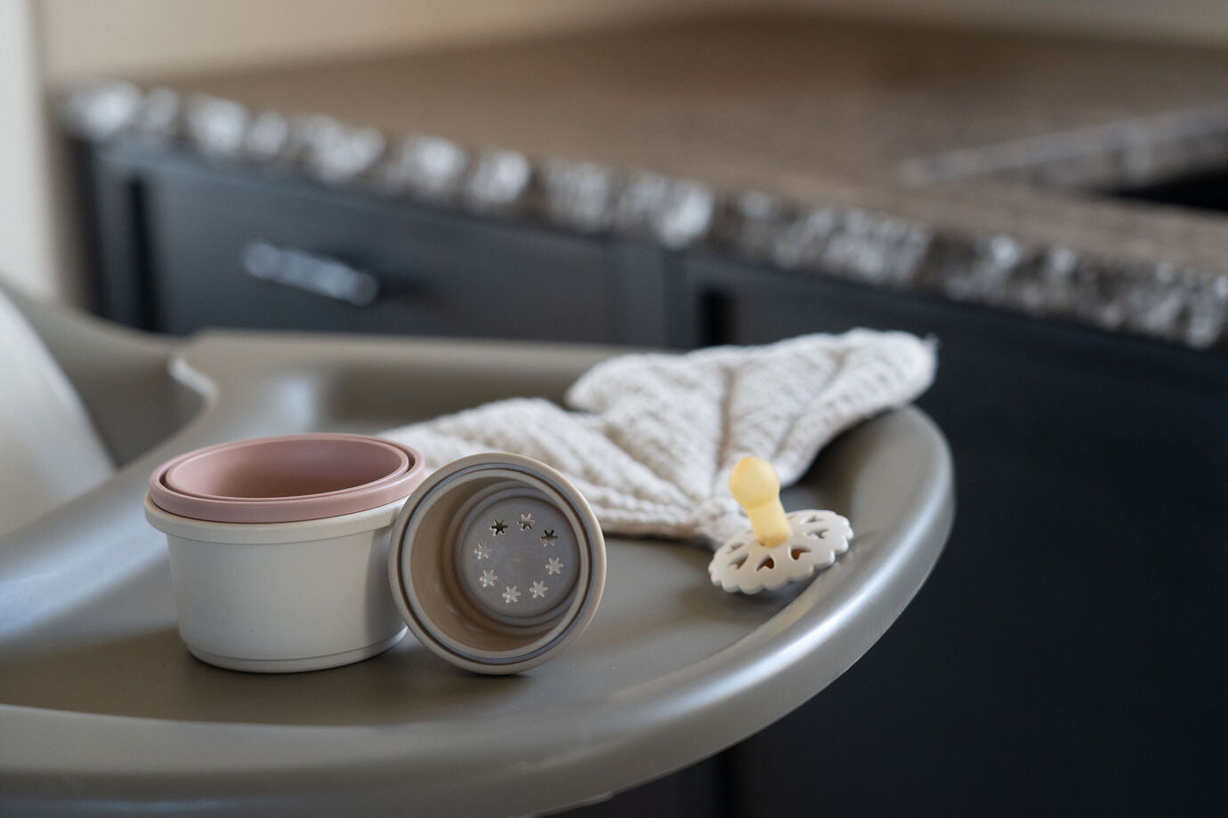 A Quax Ultimo High Chair in stone color with a modern design, featuring a high seat and adjustable legs, suitable for babies and toddlers.