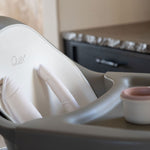 A Quax Ultimo High Chair in stone color with a modern design, featuring a high seat and adjustable legs, suitable for babies and toddlers.